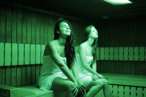 siblings sitting on wooden bench on sauna